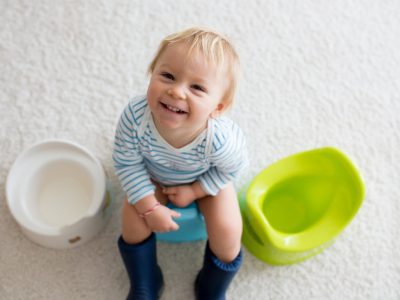 chlaoec sedí na nočníku a usmieva sa